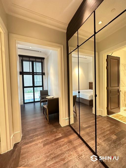 Elegant bedroom with wooden flooring and en-suite bathroom viewed from hallway