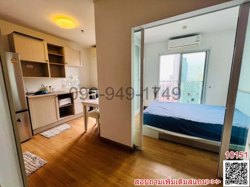 Compact apartment interior showing bedroom area, kitchenette, and a glimpse of the balcony