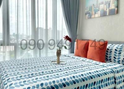Cozy bedroom with city view through large windows and patterned bedding