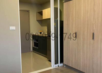 Compact bedroom with open sliding door leading to a kitchenette