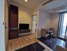 Modern living area with hardwood flooring, dining table, and TV