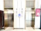 Modern elevator lobby with metallic doors and reflective ceramic tile flooring