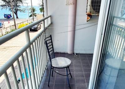 Compact balcony overlooking the beach with a single chair and a small table