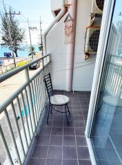 Compact balcony overlooking the beach with a single chair and a small table