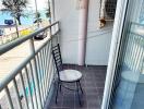 Compact balcony overlooking the beach with a single chair and a small table