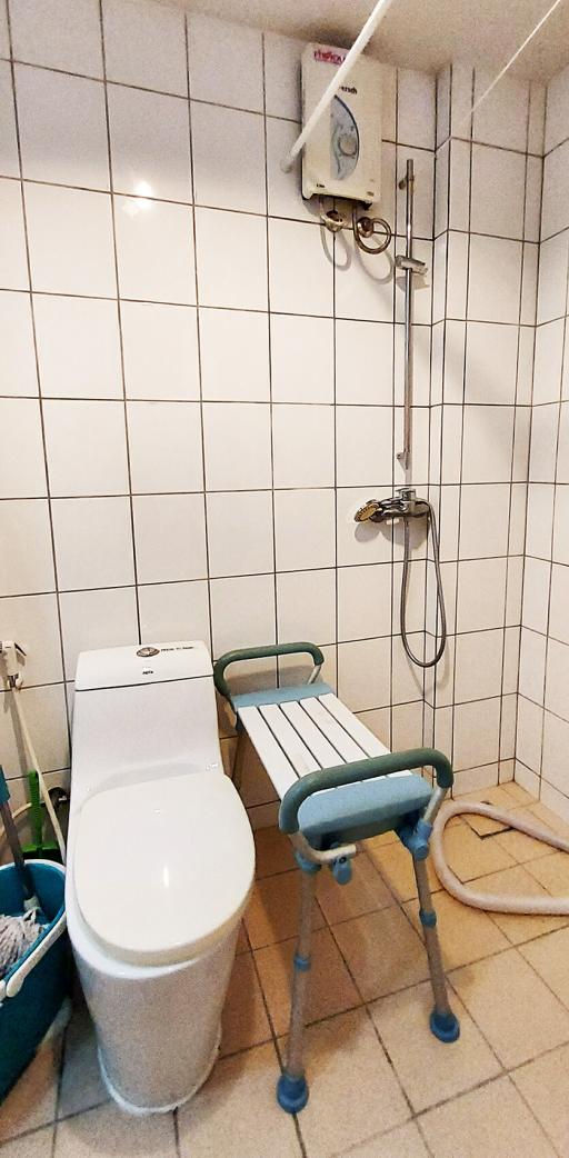 Compact bathroom with white tiling, wall-mounted water heater, and accessibility aids