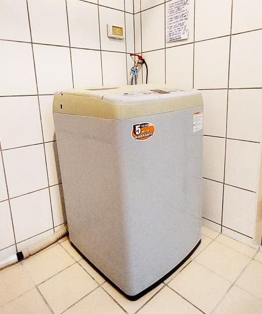 Compact laundry room with a top-load washing machine and tiled flooring