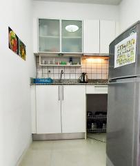 Compact and modern kitchen with white cabinetry and stainless steel refrigerator