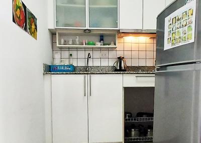 Compact and modern kitchen with white cabinetry and stainless steel refrigerator
