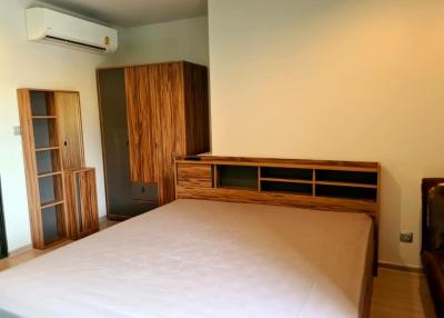 Spacious bedroom with queen-sized bed, wooden wardrobe, and air conditioning