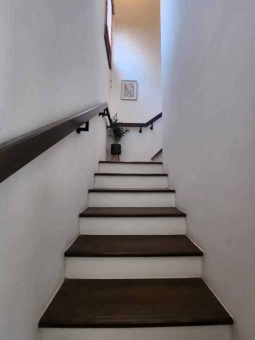 Staircase with wooden steps and white walls leading to the upper level of a house