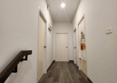 Narrow hallway with wood flooring and white walls