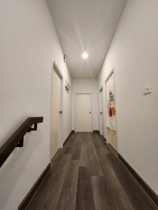 Narrow hallway with wood flooring and white walls