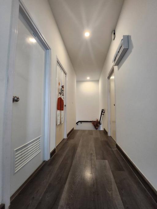 Moderately lit hallway with hardwood floors and white walls