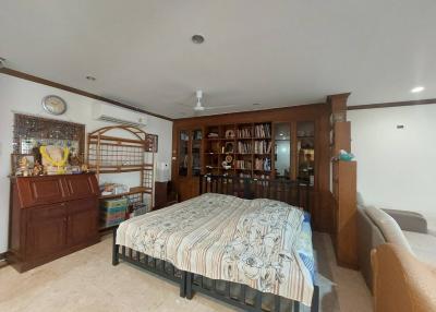 Spacious bedroom with a large bed, built-in wooden bookshelves, and various furnishings