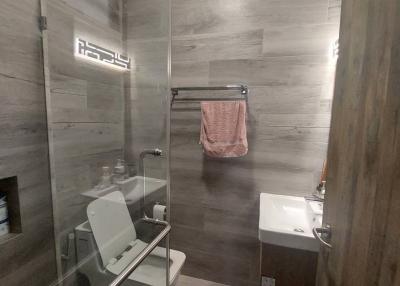 Modern bathroom with glass shower enclosure and wooden tile design