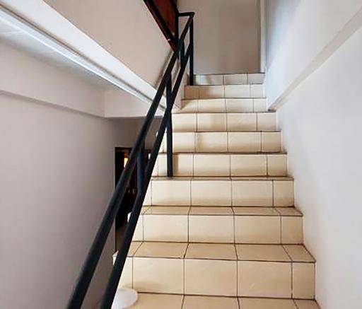 Clean staircase with white tiles and black railing