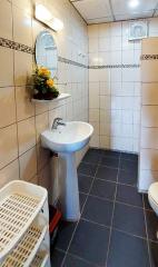 Compact bathroom with pedestal sink and tiled walls