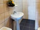 Compact bathroom with pedestal sink and tiled walls