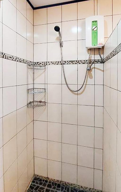 Tiled bathroom shower area with wall-mounted water heater