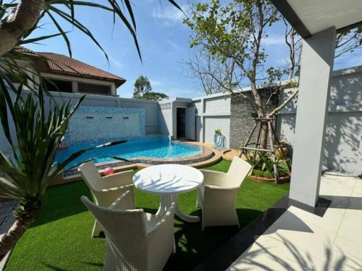 Private backyard with swimming pool, patio seating, and artificial grass