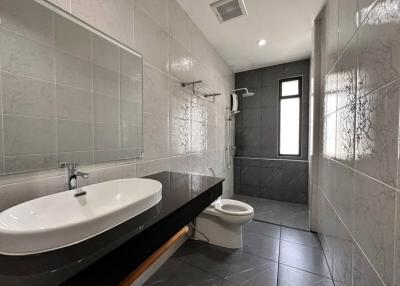 Modern bathroom with large basin, toilet, and tiled walls