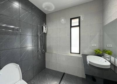 Modern bathroom with gray tiles, shower, and natural light