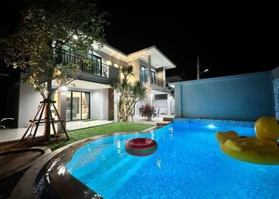 Modern two-story house with illuminated swimming pool at night