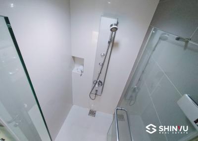 Modern white tiled bathroom with a glass shower enclosure and stainless-steel fixtures