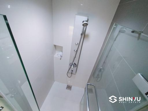 Modern white tiled bathroom with a glass shower enclosure and stainless-steel fixtures