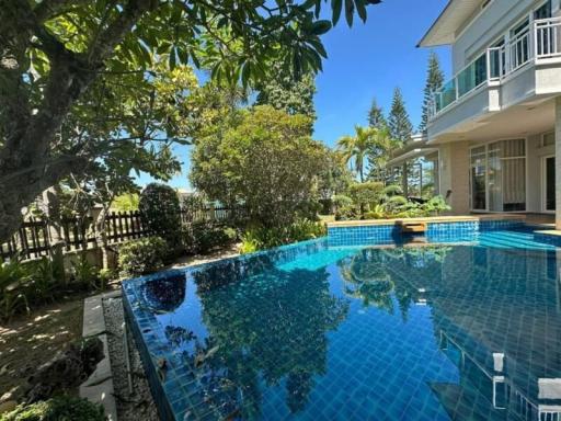 Luxurious outdoor pool with crystal clear water bordered by lush greenery and a view of a modern house