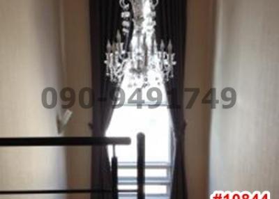Elegant chandelier over landing area with drapes and staircase