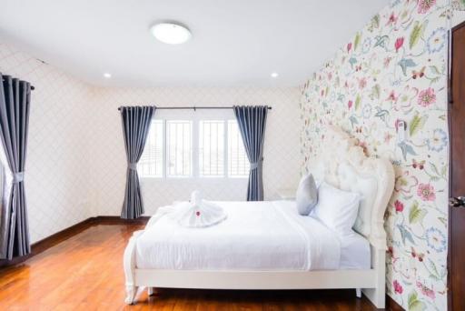 Spacious bedroom with white bedspread and floral wallpaper