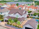 Aerial view of a residential neighborhood showcasing family houses with varying roof designs and lush green surroundings