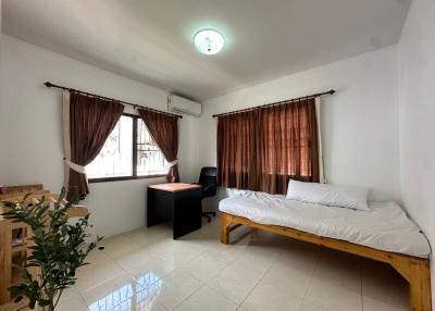 Spacious and well-lit bedroom with wooden furniture and air conditioning