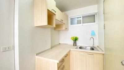 Compact modern kitchen with light wood cabinets and stainless steel sink