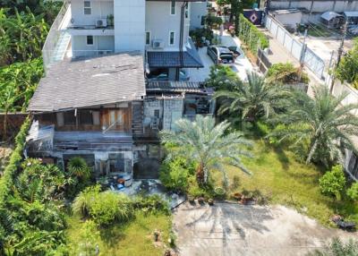 Aerial view of a residential property with a mix of modern and traditional buildings surrounded by lush greenery