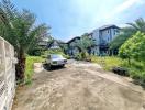 Spacious outdoor area with a car parked and lush greenery