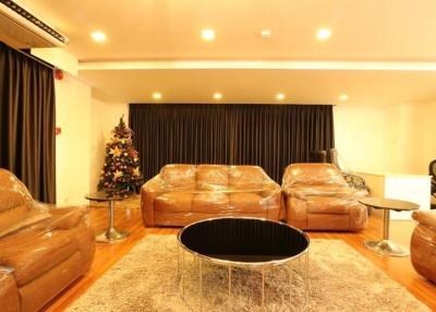 Spacious living room with protective plastic-covered sofas and a Christmas tree