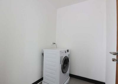 Compact laundry room with washing machine and white walls