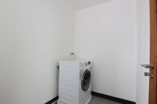 Compact laundry room with washing machine and white walls