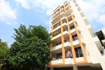 Modern multi-story residential building with balconies and a large tree in front