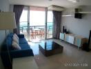 Bright living room with sea view, modern furniture, and balcony access