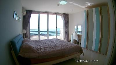 Modern bedroom interior with a comfortable bed, closet, and ocean view through wide windows