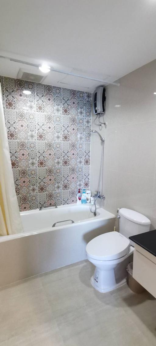 Modern bathroom with patterned tile wall, bathtub and white fixtures