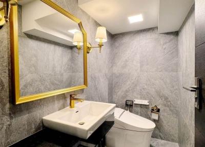 Elegant bathroom interior with gray tiles and gold-framed mirror