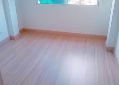 Bright empty bedroom with a large window and wooden floor