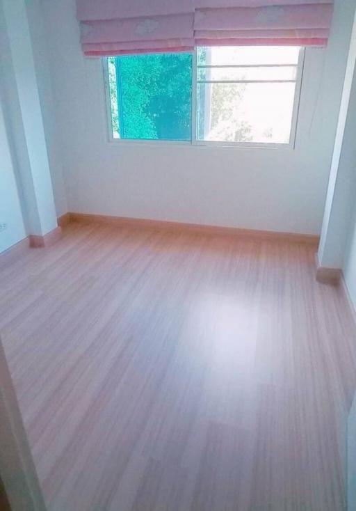 Bright empty bedroom with a large window and wooden floor