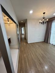 Interior view of a corridor leading to rooms with wooden flooring and a chandelier