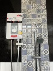 Modern bathroom wall with patterned tiles and electric shower system